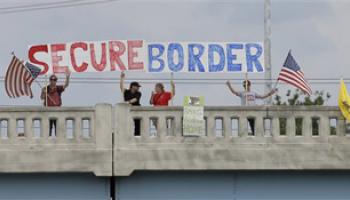 This July 18, 2014, file photo shows demonstrators with signs on an overpass in Indianapolis, to protest against people who immigrate illegally.