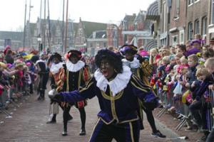 In this Nov. 16, 2013 file photo a "Zwarte Piet" or "Black Pete", jokes with children after arriving with Sinterklaas, or Saint Nicholas, by steamboat in Hoorn, north-western Netherlands. Amsterdam’s mayor and organizers of a large children’s winter festival have unveiled plans on Thursday, Aug. 14, 2014 to reform the image of “Black Pete” in order to remove perceived racist elements over a period of years.