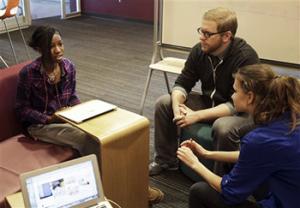English teacher Tom Rademacher talks with his high school juniors Kierra Murray, left, and Ana Silverman, right, Tuesday, Dec. 2, 2014, at Fair School in Minneapolis. Knowing that the grand jury decision not to indict a white officer who shot and killed a black teen in Ferguson, Mo., would be on the minds of his students, Rademacher put aside his lesson plans and asked them a question: How did they feel?